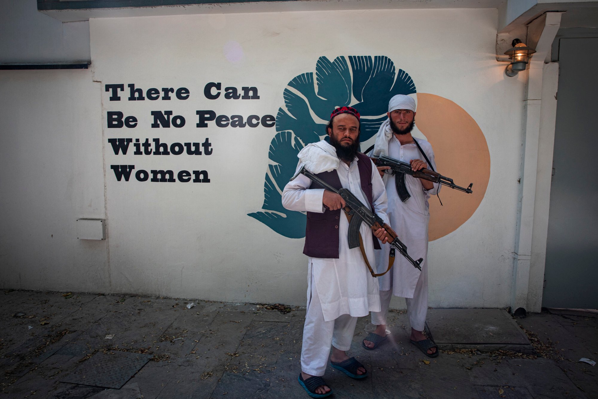 Taliban fighters pose to the camera beside a “There can be no peace without women” graffiti written on the wall of Norwegian embassy in Kabul, Afghanistan.