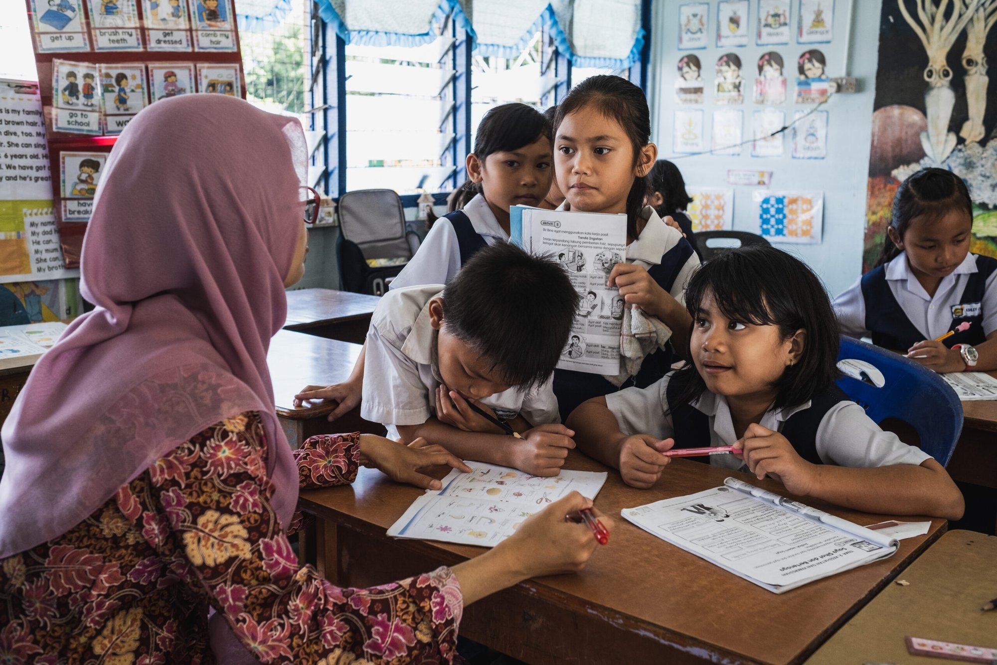 Penan children in a school room, lining up in front of their teacher.