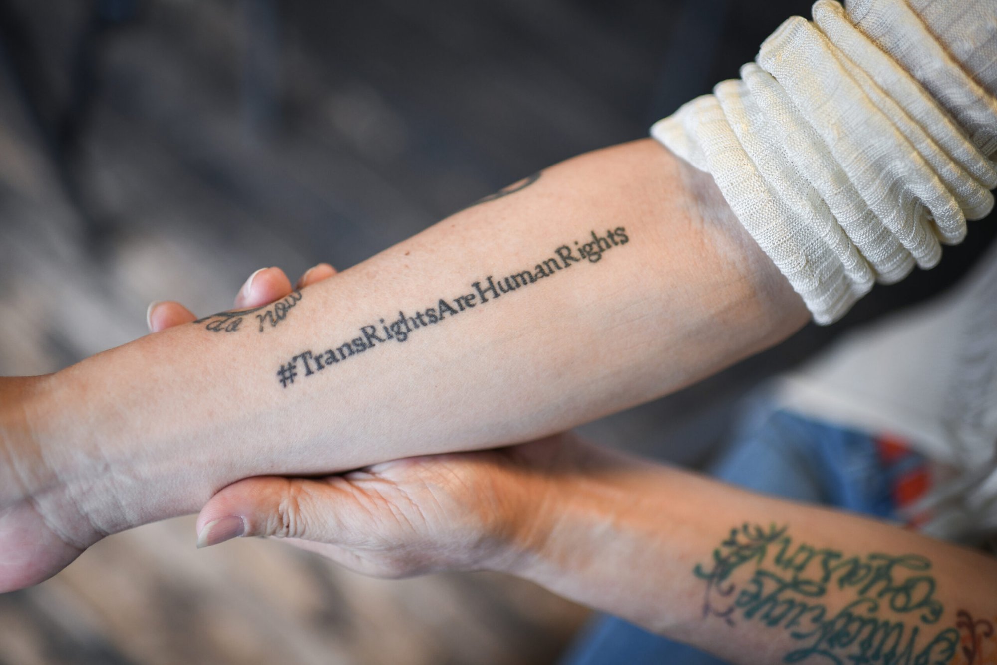 Woman’s arm with a tattoo #TransRightsAreHumanRights.