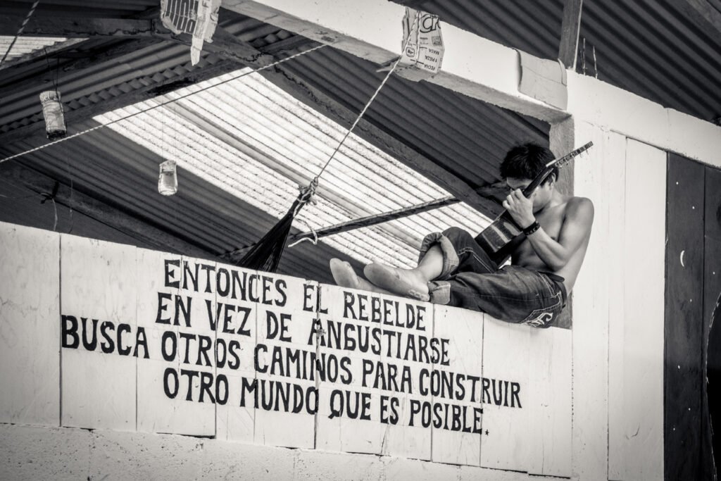 An indigenous man playing guitar on a wall in Chiapas, Mexico. Roberto Barrio.