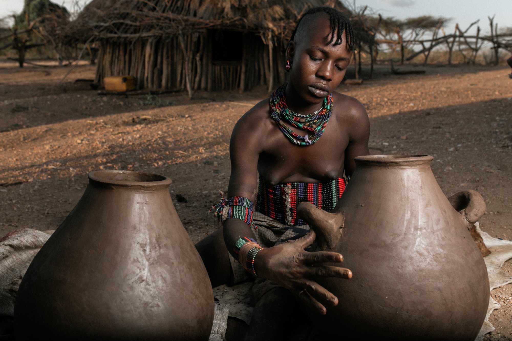 A young woman engages in the ancestral task of crafting clay pots in Omo Valley, Ethiopia.