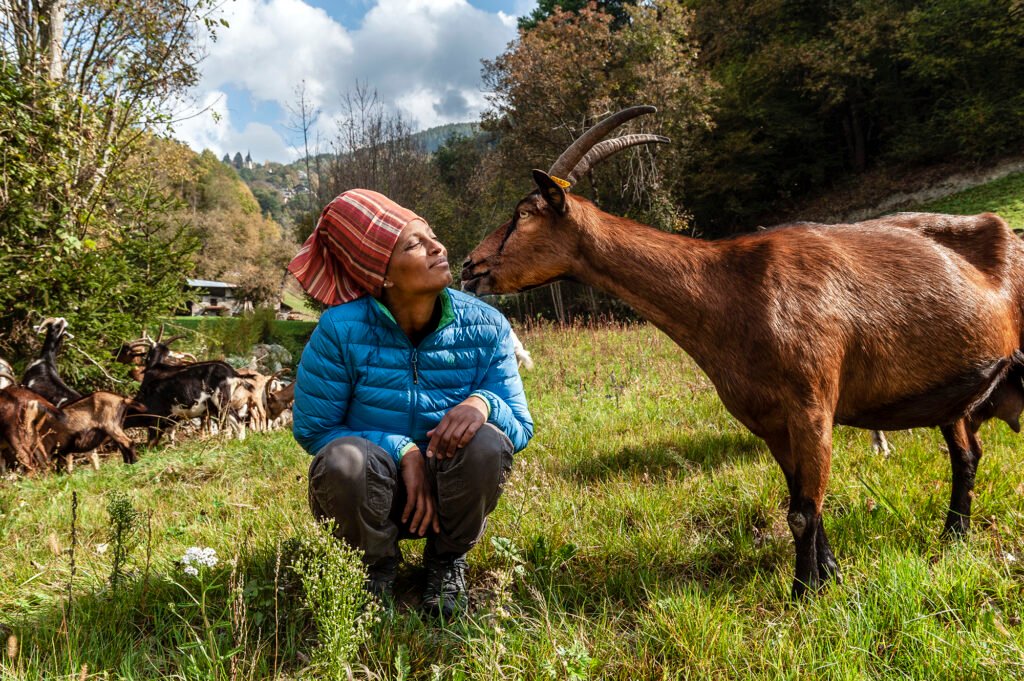 A Somalian woman is tending goats in an abandoned land in Trentino, Northern Italy.