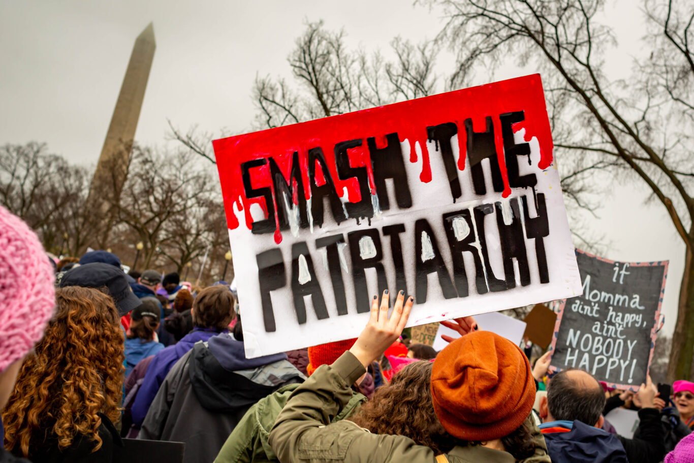 A woman holding bloody "Smash the patriarchy" sign on a protest.
