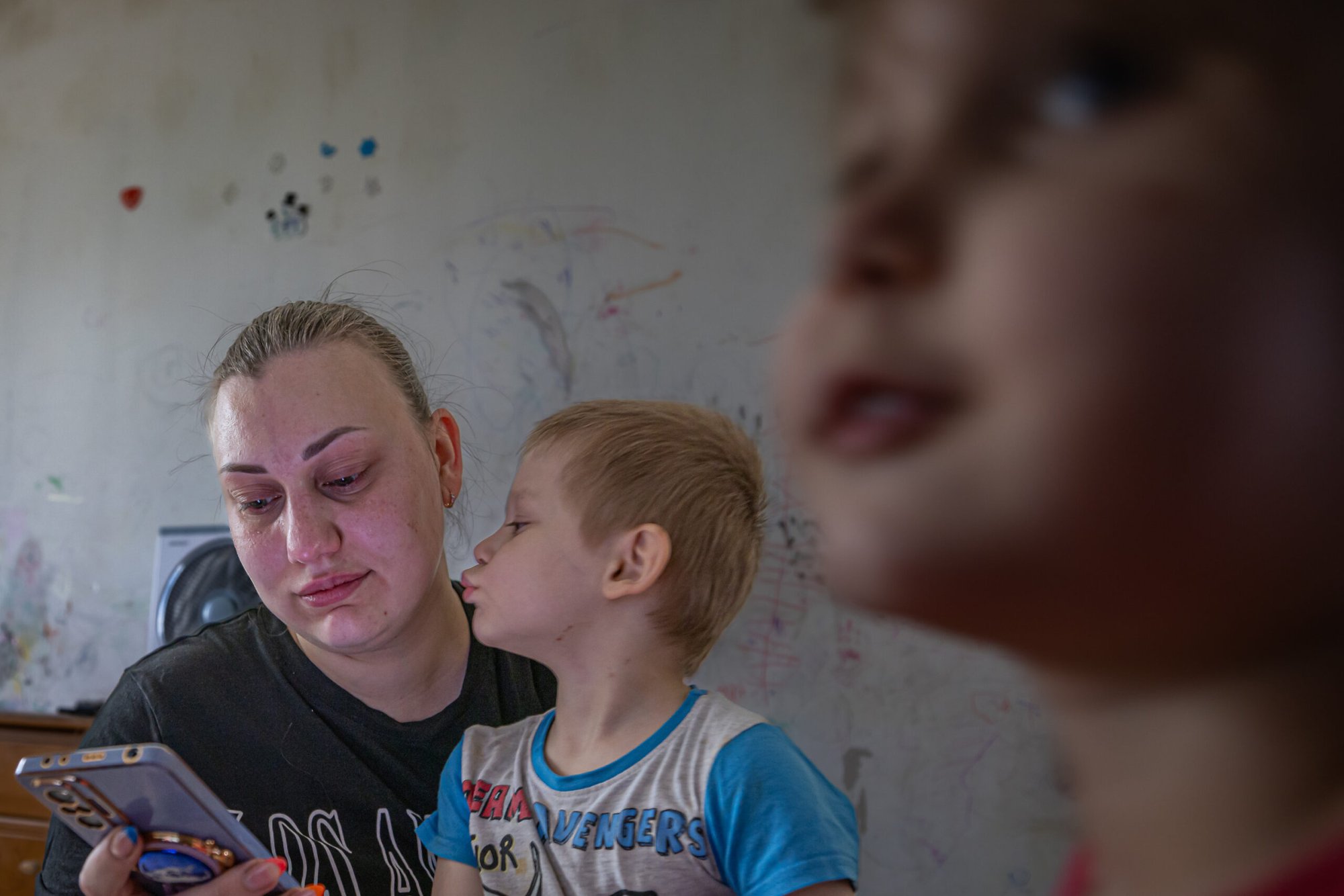 A Ukrainian refugee woman holds her child on one arm while messaging to her relatives back home in Hirnyk, Ukraine.