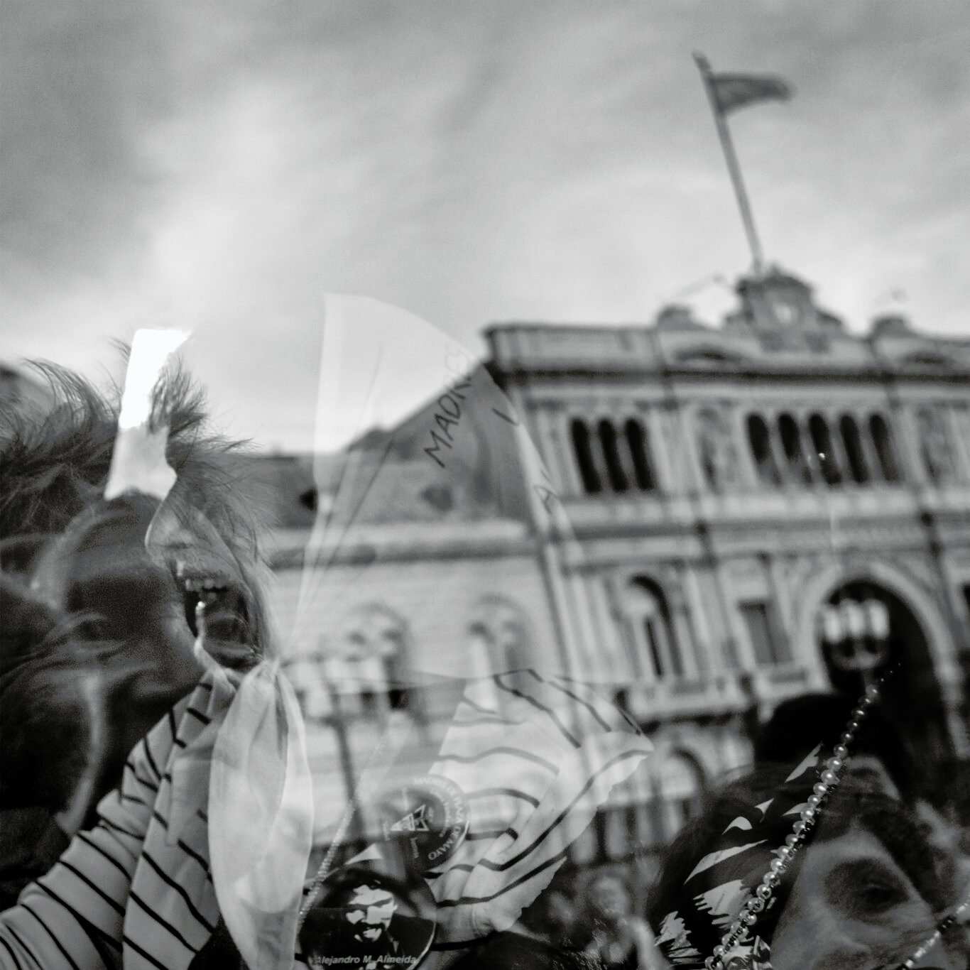 Reflection of woman from Argentinian Mothers of the Plaza de Mayo in a window, and governmental building on the background.