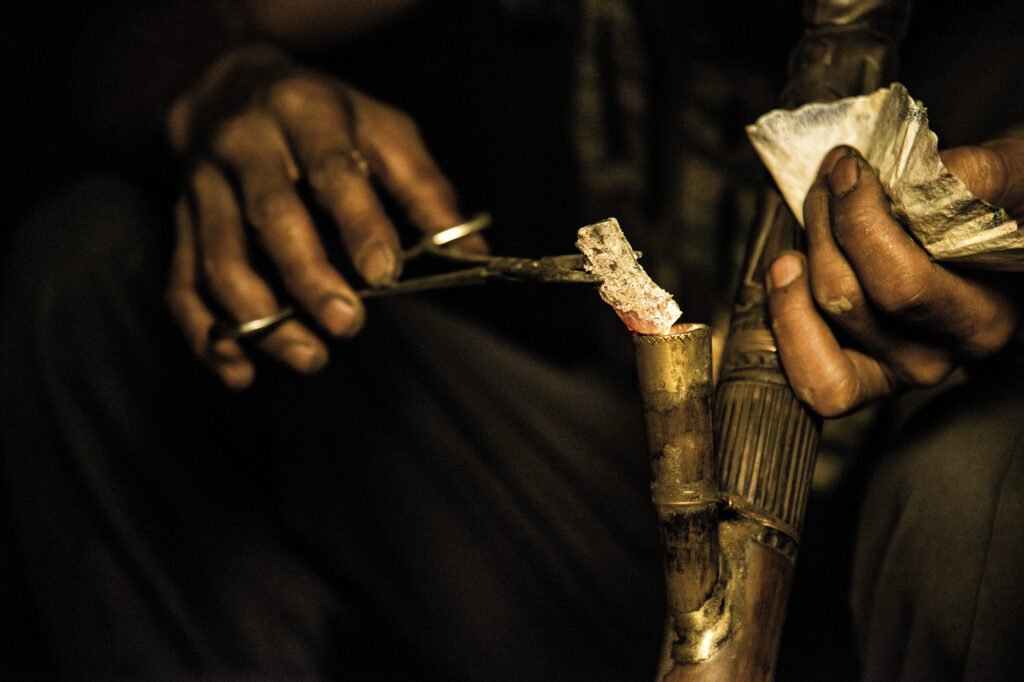 A close up of a man smoking opium with a pipe in Nagaland, India.