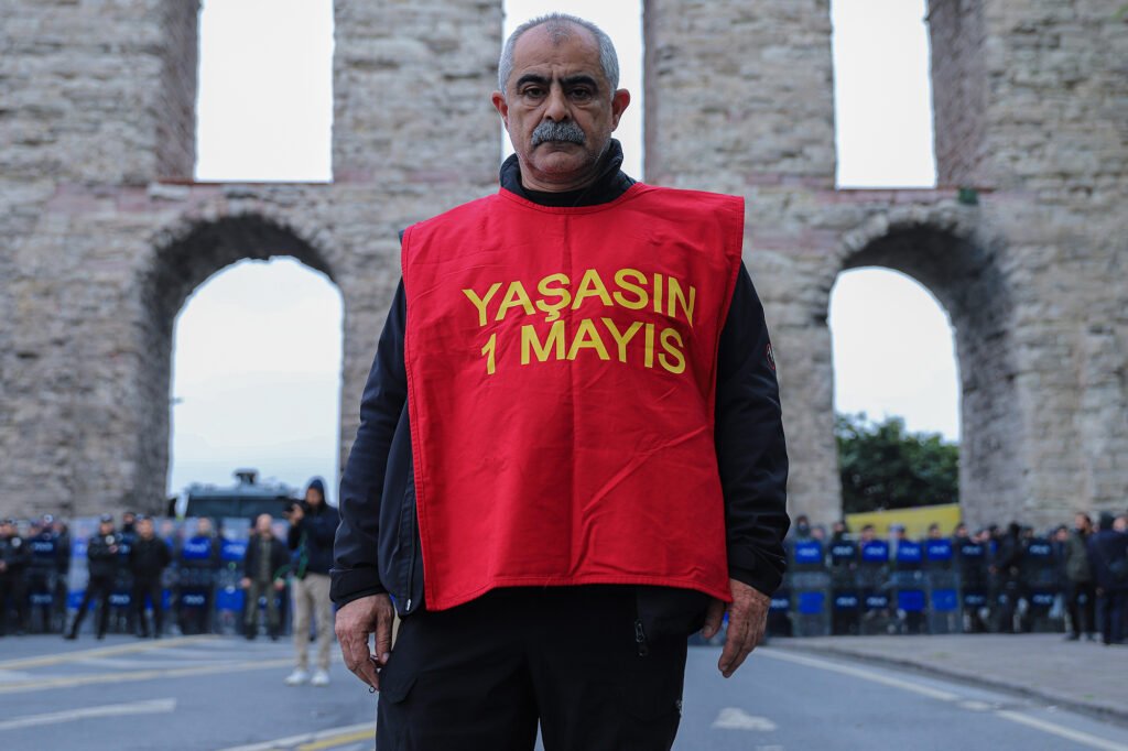A worker with "Long live May 1" standing in front of police barricade on Taksim Square, Istanbul, Turkey.