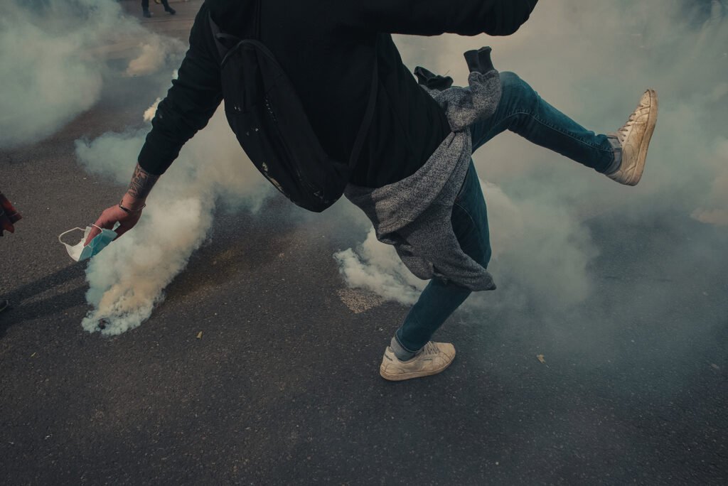 A protester kicks tear gas grenade like a footballer in Paris.