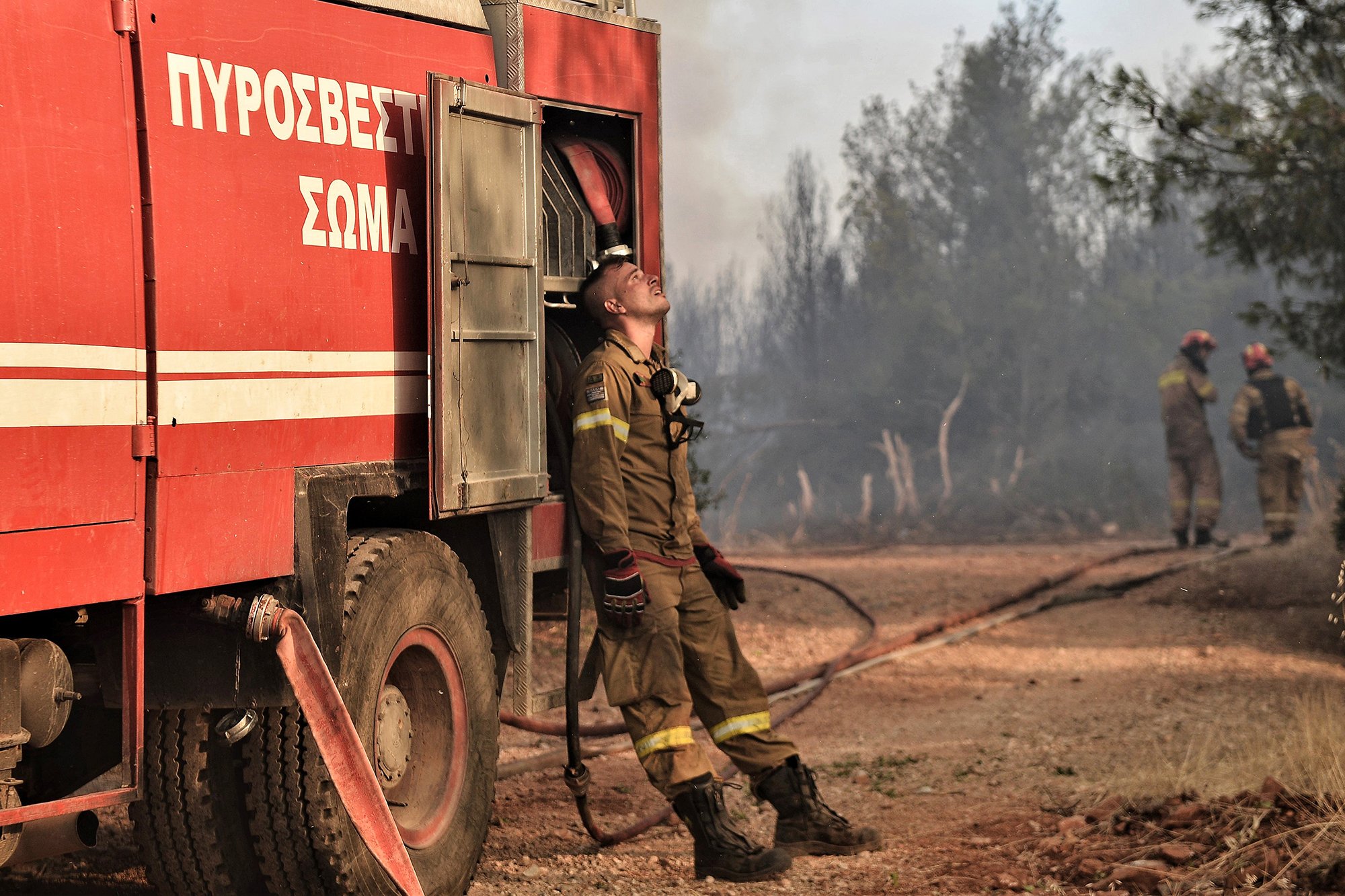 A firefighter leans to the truck during a wildfire on the western outskirts of Athens.