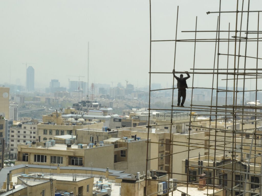A construction worker laboring hazardously high without any safety and protection equipment.