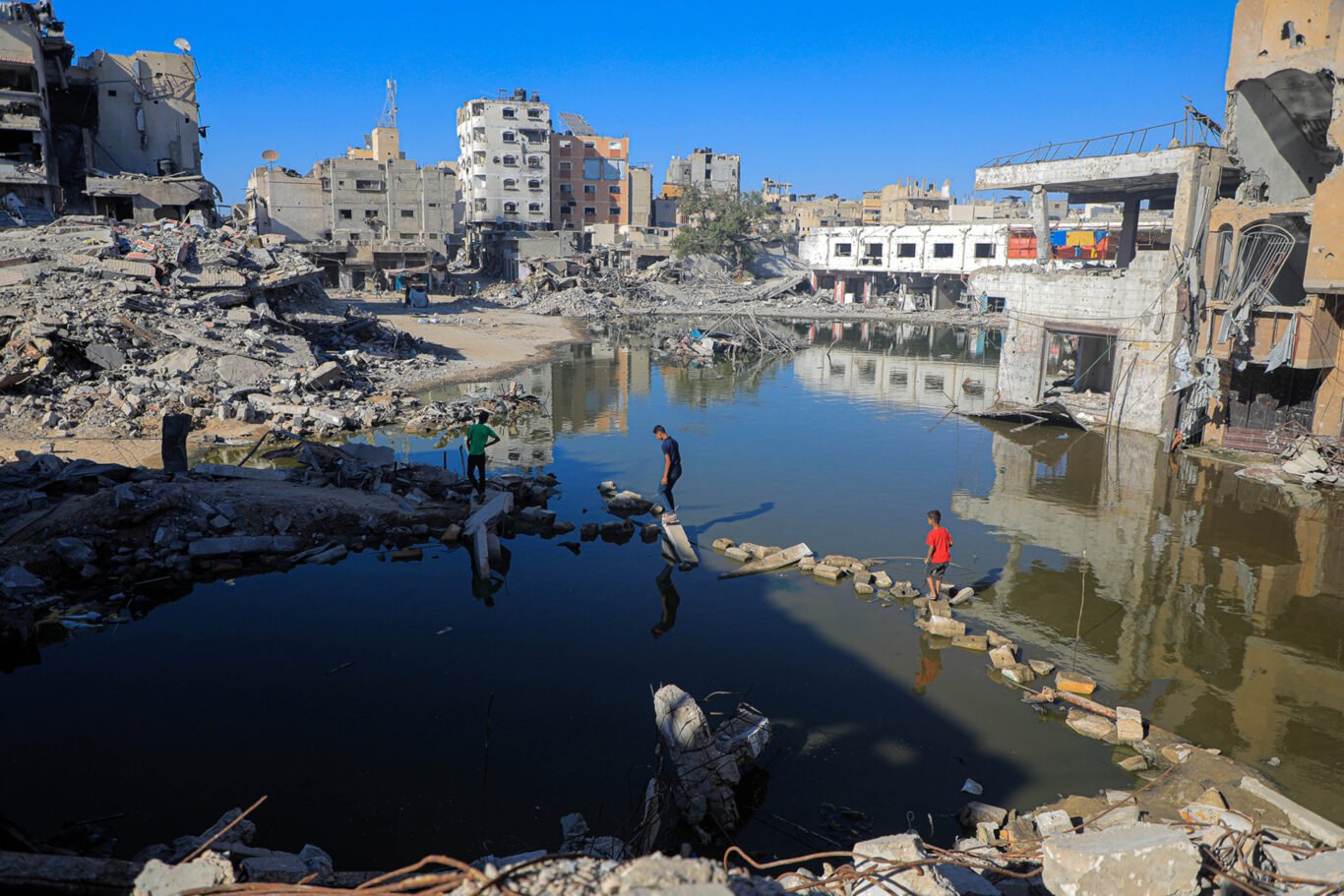 pedestrians cross ponds of wastewater in the city of Khan Younis in south Gaza as a result of the Israeli invasion that has decimated the enclave’s sewage system.
