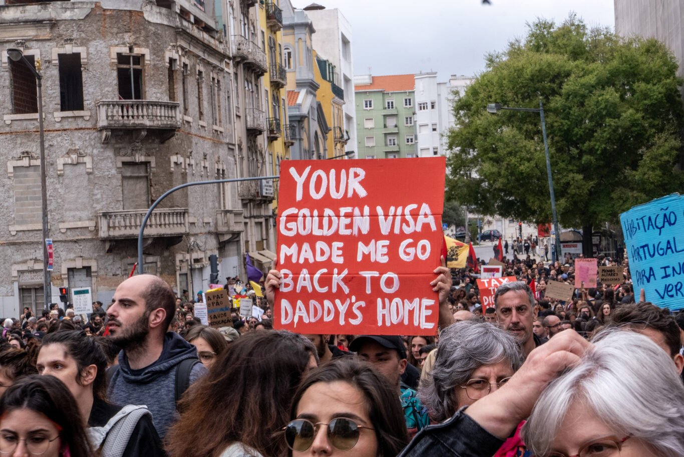 A protester holds up a ""Your Golden Visa made me go back to Daddy's home" sign during a demonstration against gentrification in Lisbon, Portugal.