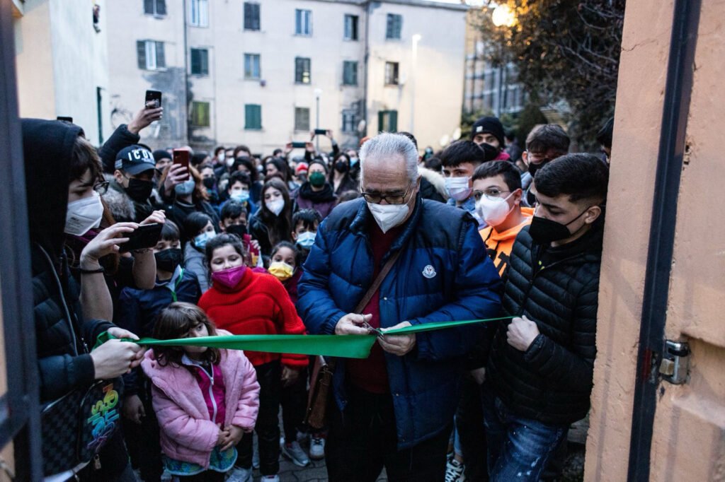 A man is cutting a ribbon to inaugurate new neighborhood house in Quarticciolo, Rome.