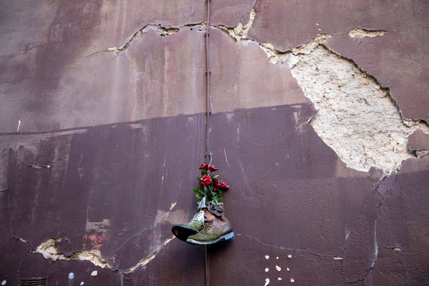 A pair of shoes and roses hanging on a broken wall in street art installation in Paris.