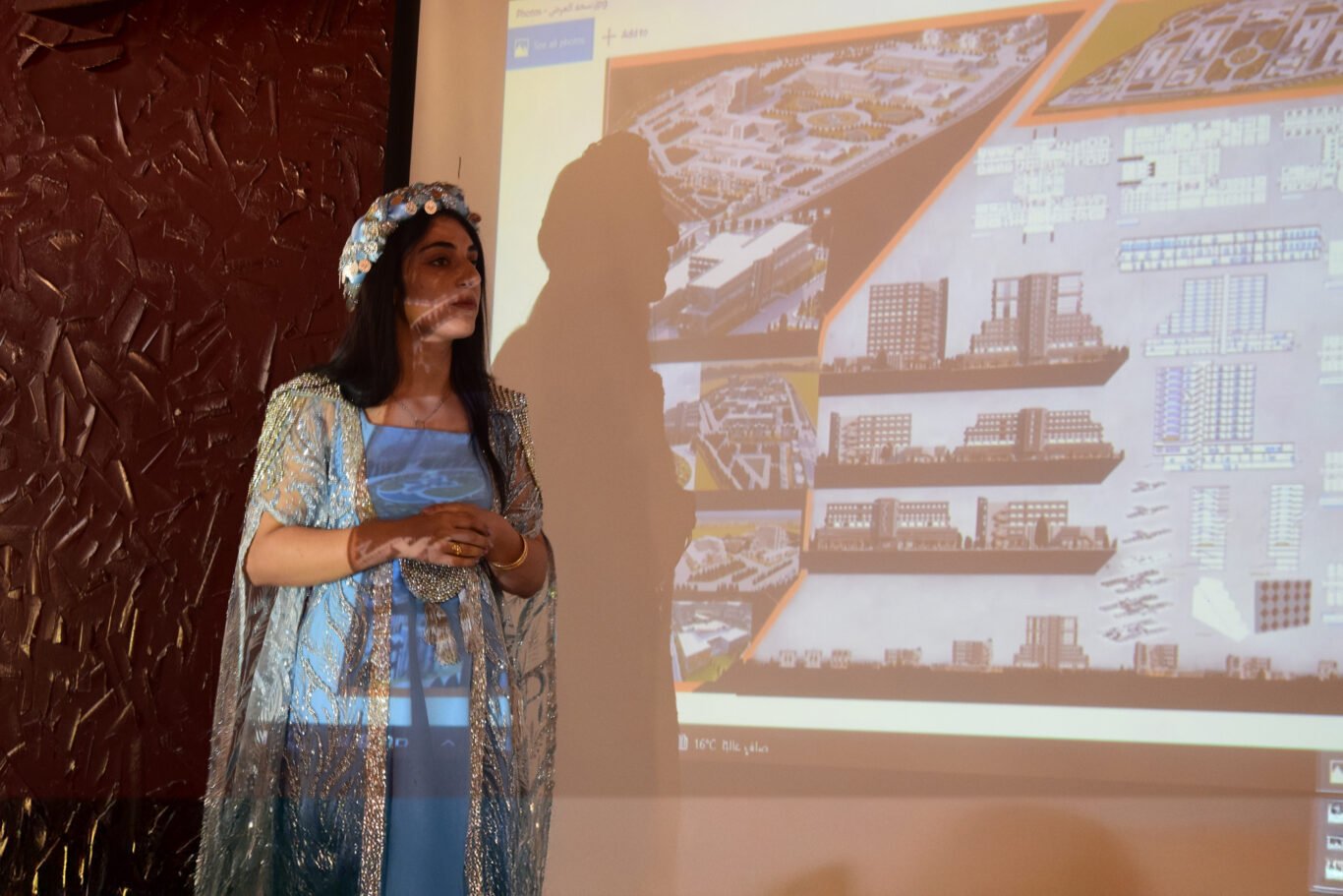 A woman in traditional Kurdish dress giving a presentation about urban engineering.