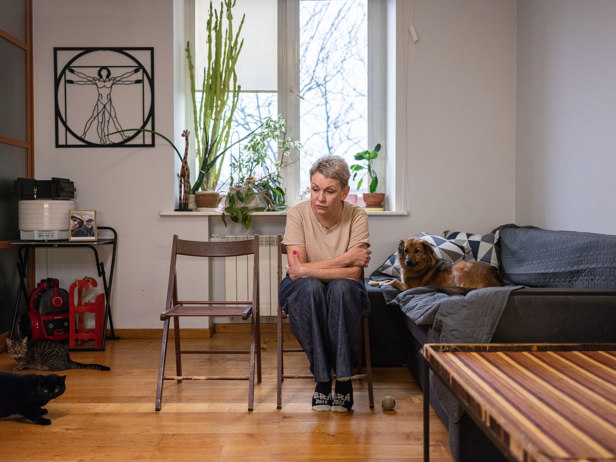 An Ukrainian mother sitting in living room, with a god on her side, thinking about her son who went missing as a soldier in Donetsk region.