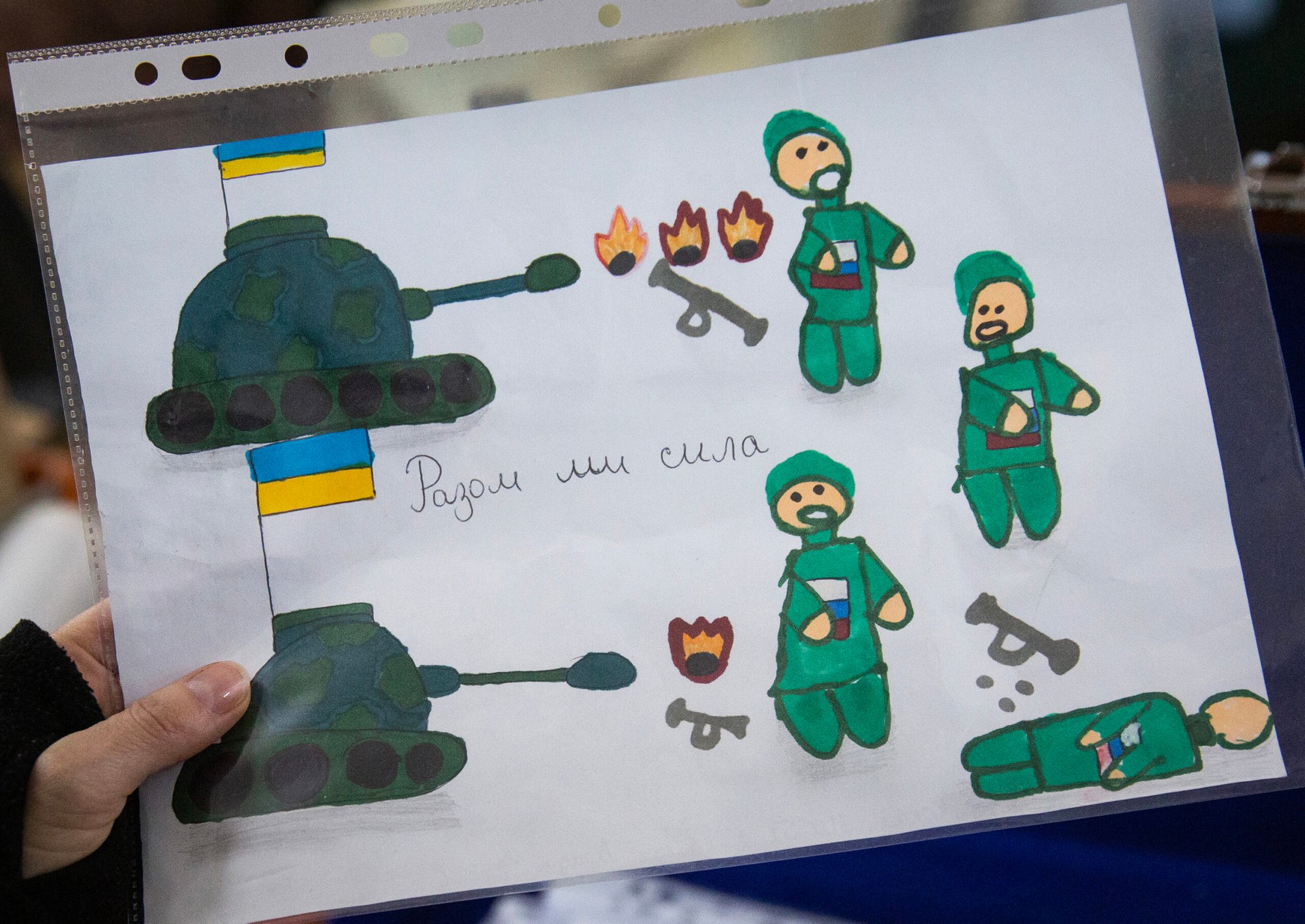 An image of child's drawing that depicts Ukrainian tanks firing Russian soldiers around the slogan "Together we are so strong."