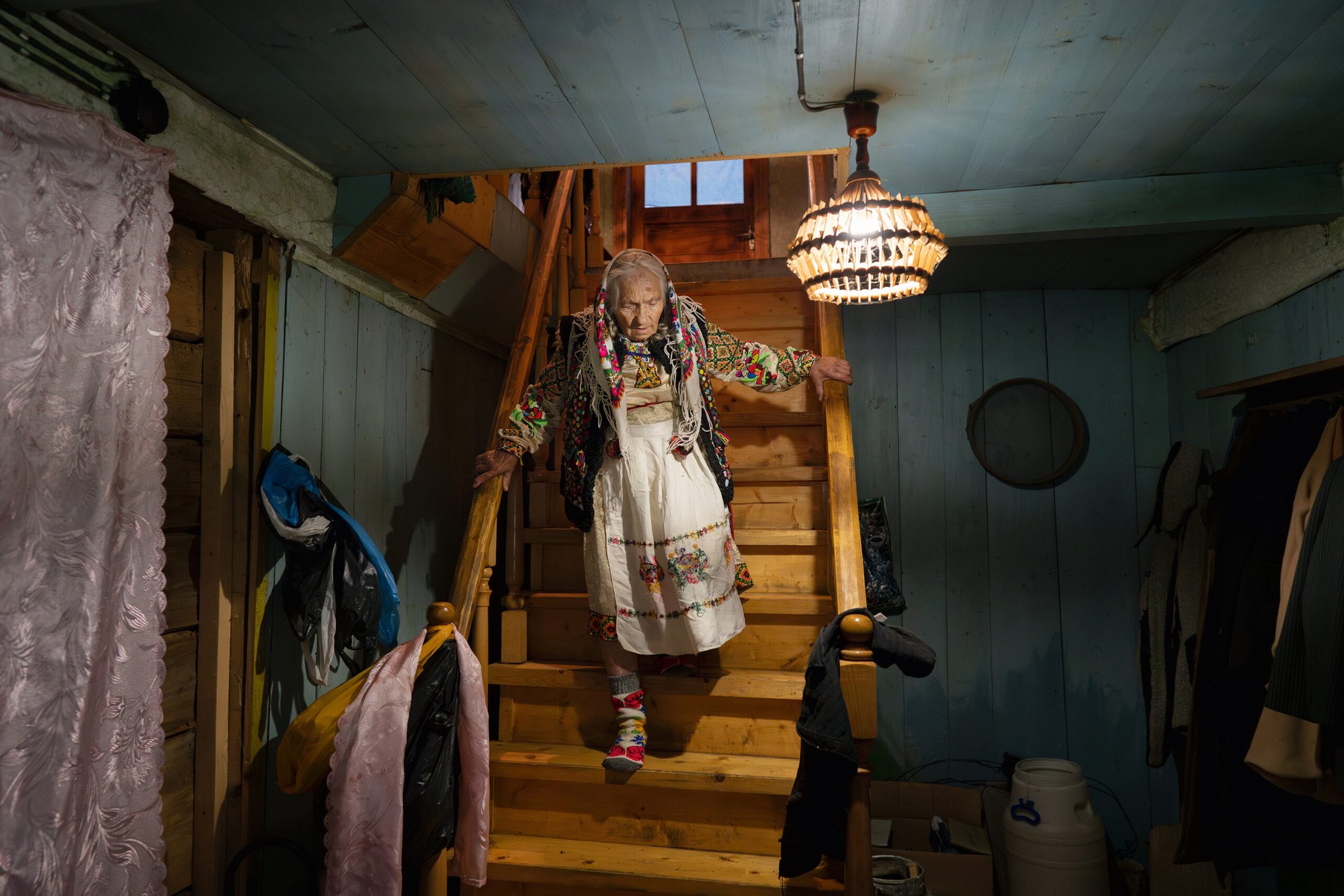 An old Ukrainian women in traditional dress is coming down the stairs of her apartment.