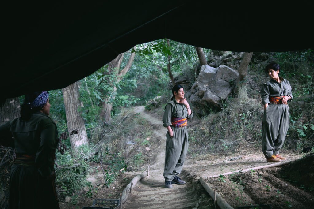 PKK Guerilla fighters at the entrance of war tunnel discuss possible relocation.