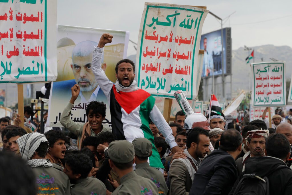 A Yemeni man wearing a dress decorated with Palestine flag is lifted on the shoulders of other Houthi protesters in Sana'a.