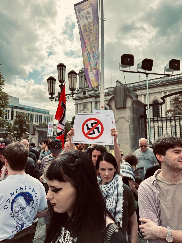 A protester holding a sign with crossed swastika and another one with Palestinian scarf during an anti-fascist protest in Belfast, Northern Ireland.