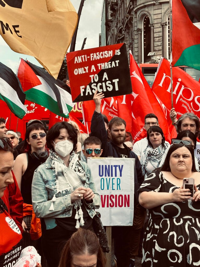 A protester holds red and black "anti-fascism is only a threat to a fascist" sign in counter-demonstration to anti-immigrant rally in Belfast, Northern Ireland.