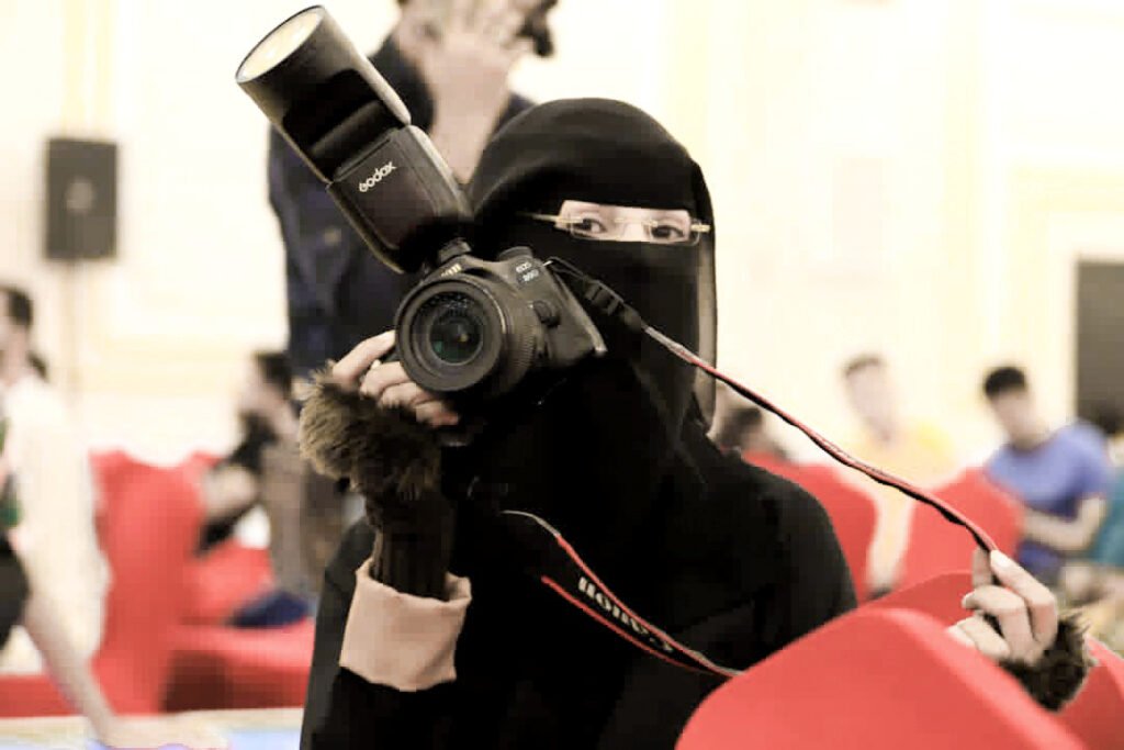 Portrait of Amat AL-Raman Alafory at work with her camera.