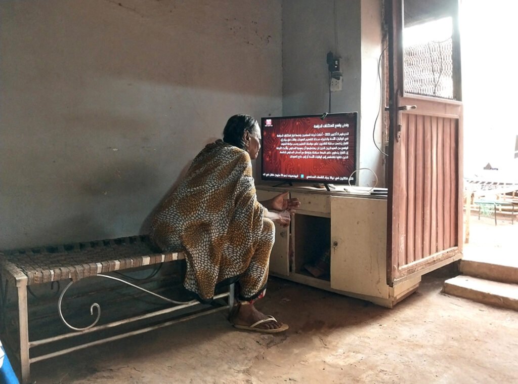 A woman who fled Khartoum three months after the war started is watching the news on Sudanese TV channel to understand the situation in Omdurman.