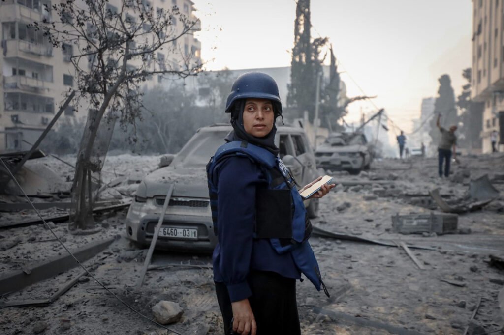 A journalist Samar Abu Elouf in press-marked armor vest in the middle of bombed neighborhood in Gaza.