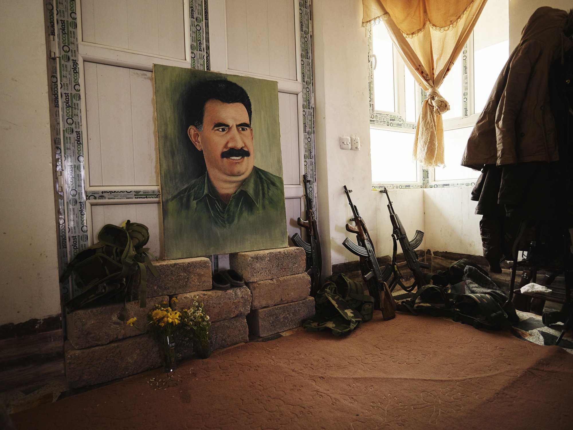 Painted Portrait of Abdullah Öcalan along with kalashikovs and combat vests.