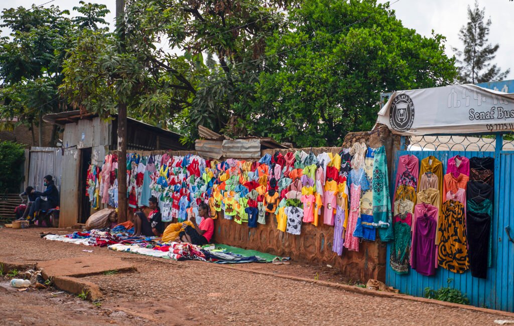 Women sell vibrant clothing on the street in Asosa, Ethiopia, balancing work and family in their everyday lives.