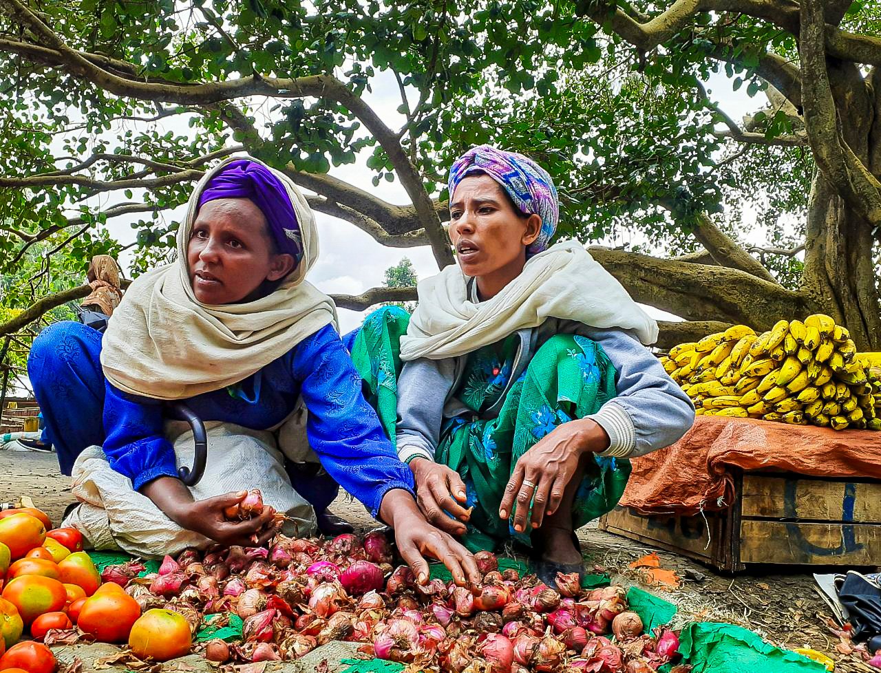 Two women buy onions in a vibrant market in Fiche Salale, Ethiopia.