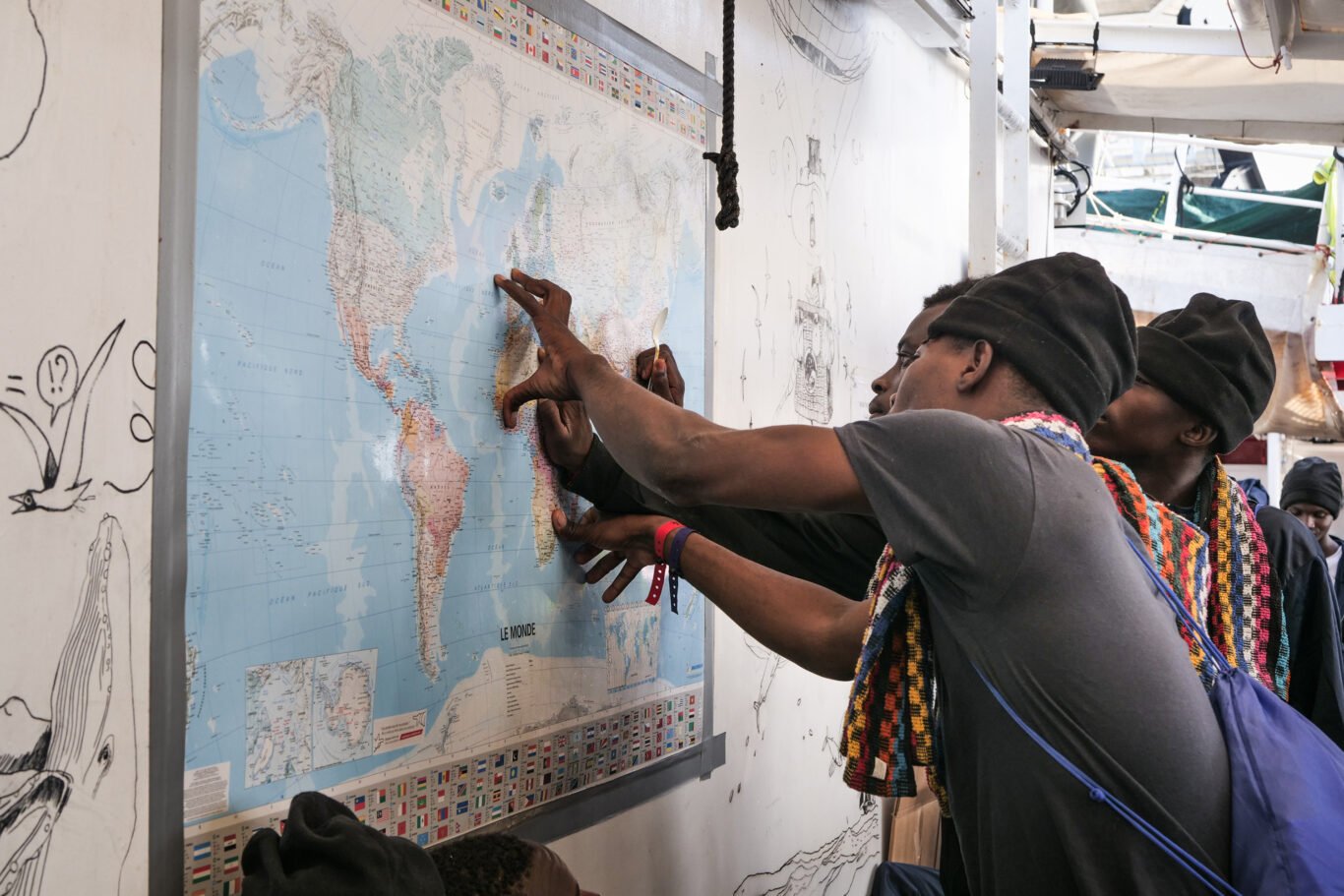 Rescued people check their itinerary on a map displayed on the main deck of the Ocean Viking