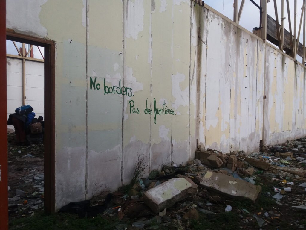 Graffiti reading “No borders / Pas de frontières” on the wall of a squat in Šid, near the Serbia–Croatia border,